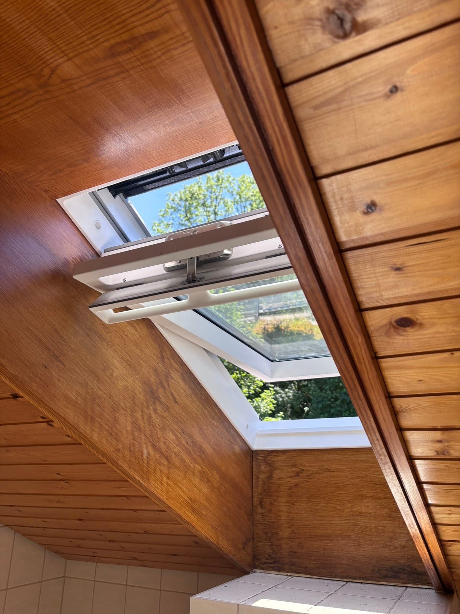 Geöffnetes Dachfenster in holzverkleideter Dachschräge